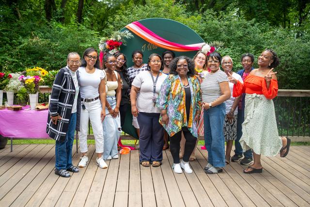 Women of CCT gathered together in front of an “I will bloom” backdrop
