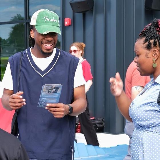 A young man smiling as he talks with a woman about a CCT flyer
